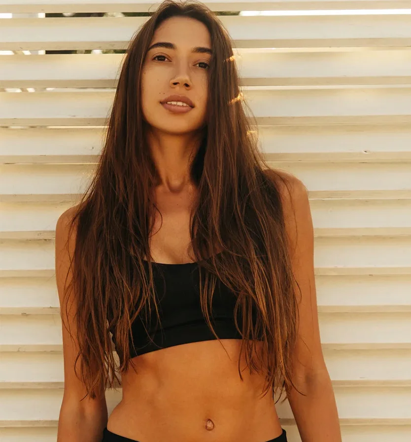 The image features a woman with long hair, dressed in a crop top and lingerie top, with a focus on her upper body. Her waist and shoulders are highlighted, emphasizing her abdomen and chest in what appears to be a photo shoot. - Laser Vein Removal in Los Angeles, CA