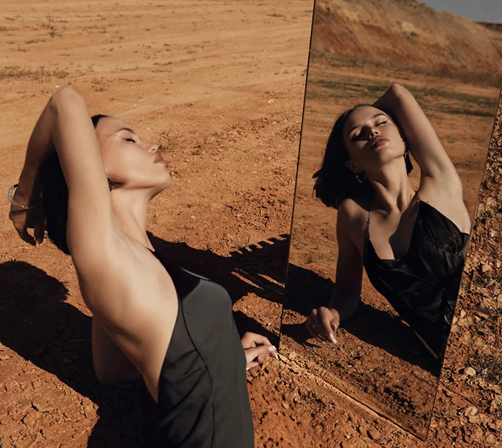 A woman posing artistically in the desert in front of a mirror after chemical peels in Nassau County and Great Neck.